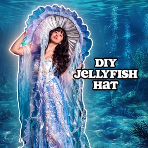 May include: A woman wearing a DIY jellyfish hat costume. The hat is a large, circular design with a silver top and blue, ruffled edges. The costume includes a flowing, blue dress and sheer, flowing fabric.