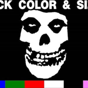 May include: Black and white Misfits skull graphic with the text "PICK COLOR & SIZE" above the skull. The skull has a wide grin with teeth and black eye sockets. A row of color swatches is below the skull.