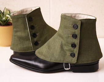 Puede incluir: Un par de polainas de lona verde con botones negros y cierre de hebilla. Las polainas se llevan sobre zapatos de cuero negro.