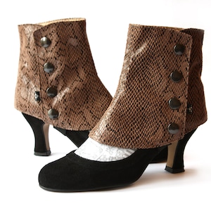 Peut inclure: Une paire de bottines à talons en faux cuir de serpent brun avec des empeignes en daim noir et des détails boutonnés à l'arrière des bottines.