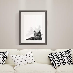 May include: Black and white watercolor painting of a cat with a white background. The cat is looking directly at the viewer. The painting is framed in a black frame.