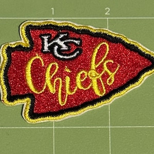May include: Embroidered patch in the shape of an arrowhead, featuring the text "Chiefs" in yellow script. The patch has a red background with a black border and a white and black logo.