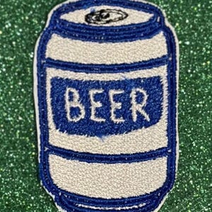 May include: Embroidered patch in the shape of a beer can. The can is white with blue accents and a blue label that reads "BEER" in white letters. The patch is on a green glitter background.
