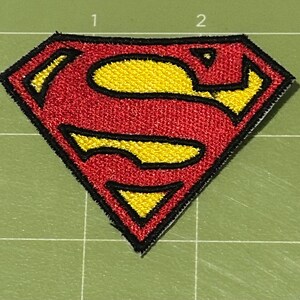 Pu&ograve; includere: Toppa ricamata con il logo di Superman. La toppa presenta una forma a diamante rossa con un emblema "S" giallo. Il design &egrave; delineato in nero. La toppa &egrave; su uno sfondo a griglia verde.