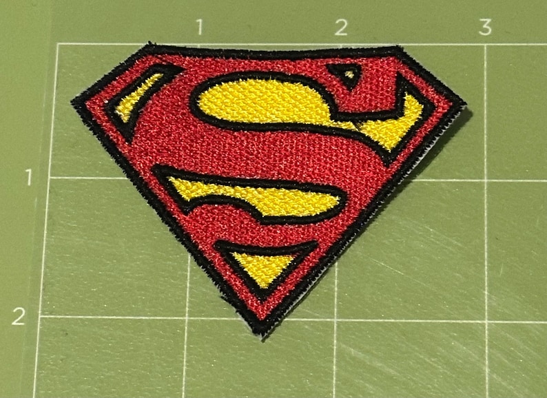 Pu&ograve; includere: Toppa ricamata con il logo di Superman. La toppa presenta una forma a diamante rossa con un emblema "S" giallo. Il design &egrave; delineato in nero. La toppa &egrave; su uno sfondo a griglia verde.