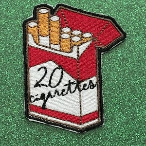 May include: Embroidered patch depicting a pack of cigarettes. The red and white pack is open, revealing several cigarettes. The text "20 cigarettes" is written on the front of the pack in black script. The patch has a black border.