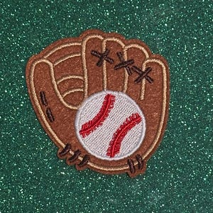 May include: A baseball patch featuring a brown baseball glove with a baseball inside. The baseball is white with red stitching. The glove has brown stitching and a tan border. The patch is on a green glitter background.