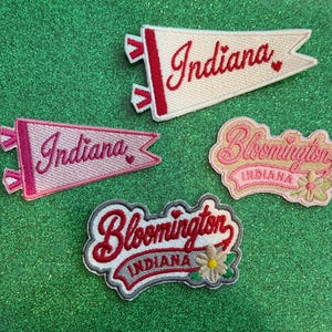 May include: Four embroidered patches featuring Indiana and Bloomington themes. Two are pennant-shaped with red or pink text, and two are shaped labels with script lettering, floral accents, and the text Indiana and Bloomington.