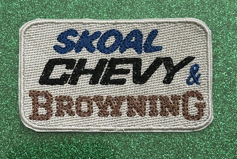 Pu&ograve; includere: Toppa ricamata con le parole "SKOAL CHEVY & BROWNING" in blu, nero e marrone. La toppa ha uno sfondo grigio chiaro e un bordo cucito. La toppa &egrave; rettangolare con angoli arrotondati.