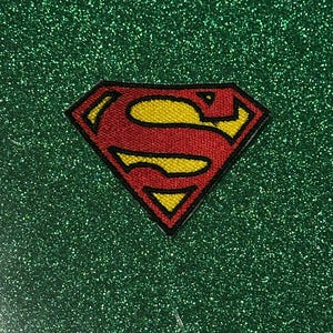 Pu&ograve; includere: Toppa ricamata con il logo di Superman. L'iconico scudo "S" rosso e giallo &egrave; posto su uno sfondo verde glitterato. La toppa presenta un design dettagliato con un contorno nero.