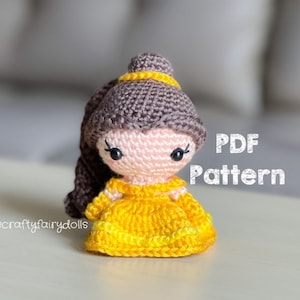 May include: A crocheted amigurumi doll of Belle from Beauty and the Beast. The doll is wearing a yellow dress and has brown hair. The image includes the text "PDF Pattern".