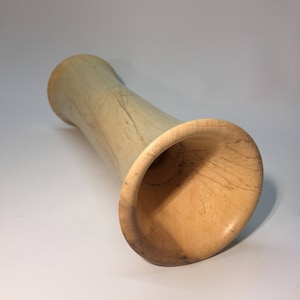 May include: A light brown wooden vase with a flared opening. The vase is made of wood with a natural grain pattern.