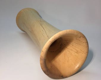 May include: A light brown wooden vase with a flared opening. The vase is made of wood with a natural grain pattern.