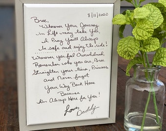 Handwritten note or message engraved onto white wood with grey frame