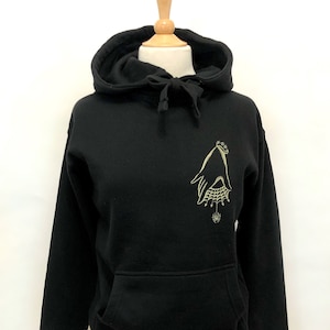 May include: Black hooded sweatshirt with a gold embroidered design of a hand with a spider web and a spider on the left chest.