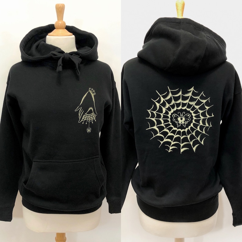 May include: Black hoodie with a white spiderweb and butterfly design on the back and a white hand with a crown and spider design on the front.