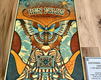 May include: A rectangular concert poster for Ben Folds with the Asheville Symphony featuring a large central butterfly with piano key wings, orange and teal colors, and a star. Includes a white certificate of authenticity card with black text.
