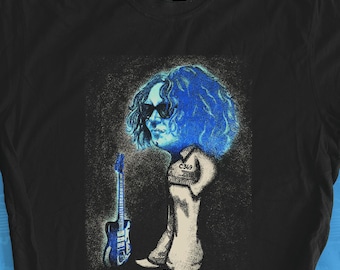 May include: A black short-sleeve t-shirt featuring a graphic print of a stylized figure with voluminous blue hair, wearing sunglasses and light-colored trousers, standing next to a blue electric guitar. The design has a textured, sketch-like appearance.