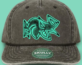 May include: A dark gray cap with a teal graffiti-style design. The cap has a curved brim and a rope detail. The text "LEGACY SKULLY" is on a small tag on the brim. The visor board is made from recycled content.