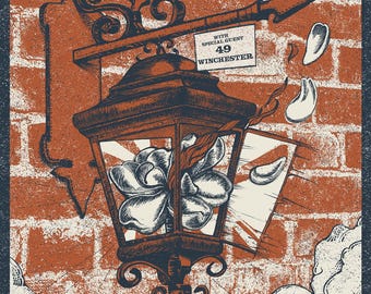May include: Concert poster for Eric Church's Free the Machine Tour, featuring a detailed illustration of a lantern with a flower inside, set against a brick wall. Includes tour details: North Charleston, SC, March 7, 2026.