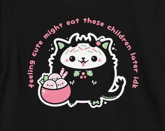 May include: Black t-shirt with a cute cartoon black cat wearing a Santa hat and holding a bowl of mochi. The text on the shirt reads "feeling cute might eat these children later idk".