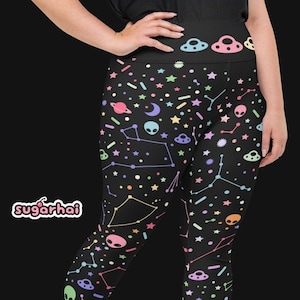Puede incluir: Leggins negros con un estampado colorido de estrellas, planetas, extraterrestres y constelaciones.