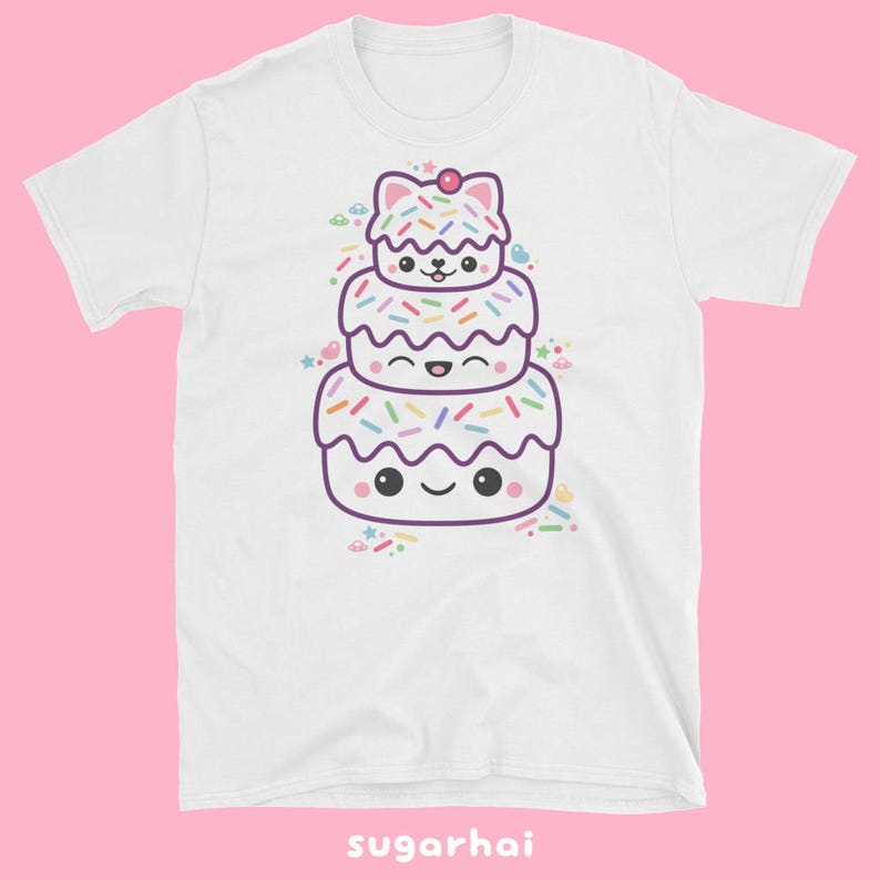 May include: White t-shirt featuring a stacked cartoon cake design with a cat on top. The cake has colorful sprinkles and smiling faces. The text "sugarhai" is at the bottom.