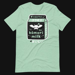 May include: A light green t-shirt featuring a graphic of a black milk carton with a bat illustration and Japanese text. The text includes "sugarhai", "kōmori milk", and "delicious". The design has a cute, kawaii aesthetic.