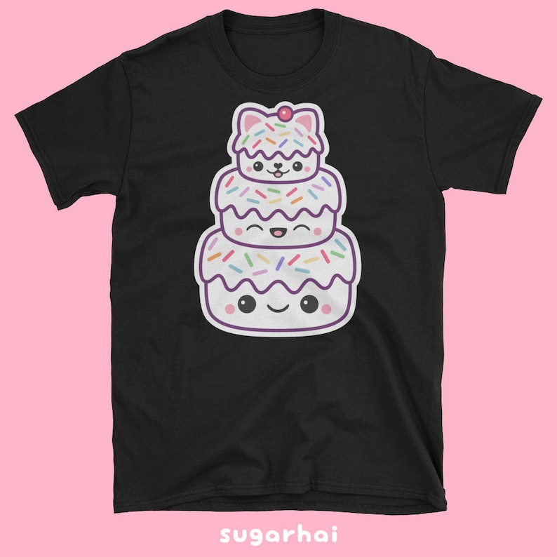May include: Black t-shirt featuring a stacked cartoon dessert with a cat-like shape on top. The dessert has white frosting, colorful sprinkles, and smiling faces. The text "sugarhai" is at the bottom.