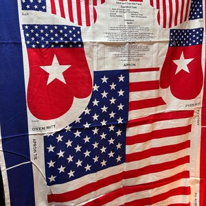 May include: Fabric panel featuring an American flag design with red and white stripes and blue fields with white stars. Includes cut-out patterns for an apron and oven mitts. Text includes "Apron and Oven Mitt Panel" and instructions.