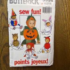 May include: A Butterick 5594 sewing pattern envelope titled sew fun! and points joyeux! featuring illustrations of infants in various costumes including a pumpkin, a clown, a rabbit, a leopard, a jester, and a ladybug with red and black details.