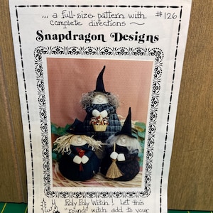 May include: A sewing pattern sheet titled Snapdragon Designs #126 featuring three round fabric witch dolls with black hats, yarn hair, and dark clothing. The sheet includes text instructions and a drawing of a squirrel holding a flower.
