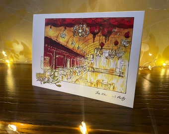 Może przedstawiać: Aquarela przedstawiająca przyjęcie noworoczne w czerwonym i złotym pokoju z żyrandolami i czerwonymi lampionami. Tekst "The New Year's Party" znajduje się na dole kartki.