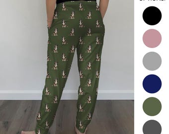 Op de afbeelding: Groene pyjamabroek met een herhalend hondenpatroon. De broek heeft een taille met trekkoord en geribbelde enkels. De tekst "6 COLOR OPTIONS!" wordt weergegeven naast een kleurenpalet van zwart, roze, grijs, marine, olijf en donkergrijs.