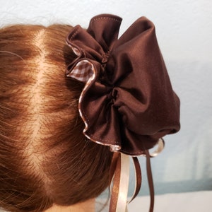 May include: A brown satin hair scrunchie with a gingham trim and two brown and cream ribbon ties.