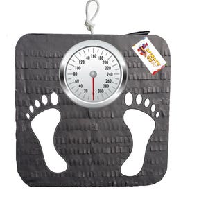 May include: A gray piñata shaped like a scale, featuring a gauge with numbers and a red needle. White footprints are on the front. A tag with the text "APINATA" is attached.