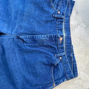 May include: A pair of blue denim jeans with a classic five-pocket style. The jeans have a straight leg and a dark wash.