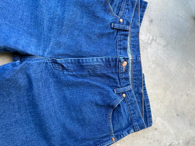 May include: A pair of blue denim jeans with a classic five-pocket style. The jeans have a straight leg and a dark wash.
