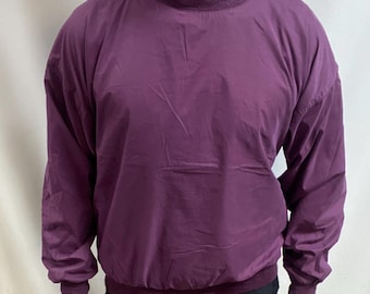 May include: A plum-coloured pullover windbreaker with a ribbed collar, cuffs, and hem. The long-sleeved jacket is paired with black trousers. The outfit is suitable for outdoor activities.