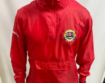 May include: A vibrant red jacket with a half-zip, front pocket, and a high collar. The jacket has a patch on the right chest with the text "JACKSONVILLE XXXIX BEST COMMITEE". The jacket is worn with black trousers.