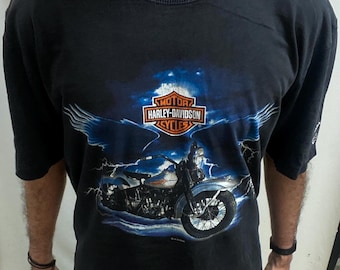 May include: Black Harley-Davidson t-shirt with a motorcycle graphic, wings, and lightning. The Harley-Davidson logo is above the motorcycle. The shirt has a crew neck and short sleeves.