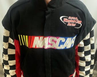 May include: Black NASCAR Winston Cup Series jacket with a checkered pattern on the sleeves. The jacket features the NASCAR logo in white, red, and blue, with a multi-coloured stripe design.