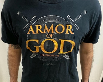 May include: Black t-shirt featuring the words "ARMOR OF GOD" in gold, with a shield and crossed swords design. The text "Ephesians 6:11" is below the shield.