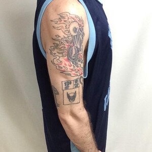 May include: Navy blue sleeveless jersey with light blue trim. The jersey is visible from the side. The arm has tattoos, including a skull with flames and a Wolverine logo.