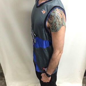 Puede incluir: Camiseta de baloncesto gris y azul con ribete negro. La camiseta presenta la palabra "Arizona" y un logotipo. La camiseta es sin mangas y tiene un dise&ntilde;o de cuello en V. La camiseta la lleva una persona.