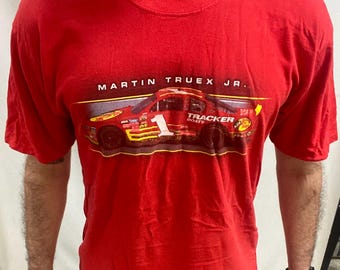May include: Red t-shirt with a graphic of a race car, the number 1, and the text "MARTIN TRUEX JR." and "TRACKER BOATS". The shirt has short sleeves.