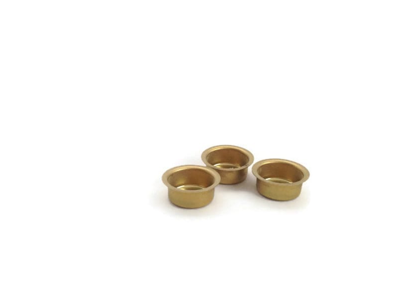 May include: Three gold-colored metal candle holders. The candle holders are round and have a slightly raised lip around the edge.