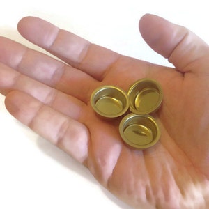 May include: Three small, round, gold-colored metal candle holders.