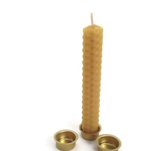 May include: A honeycomb beeswax candle with a white wick, sitting on two gold metal candle holders.