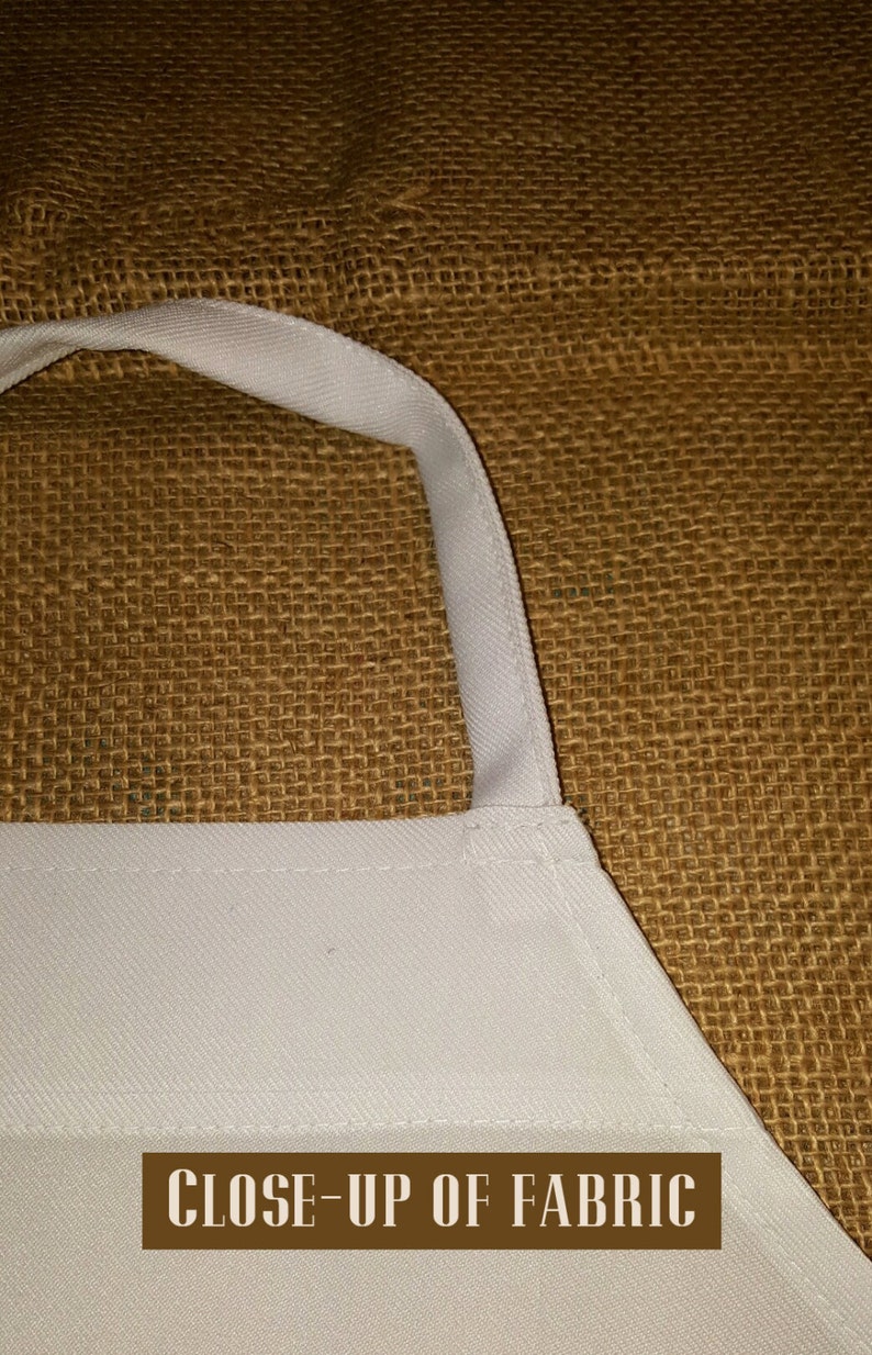 May include: Close-up of a white apron with a brown burlap background. The apron has a white strap and is made of a soft, woven fabric.